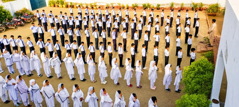 RBES students in white uniforms lined up in rows for the morning assembly in the school courtyard