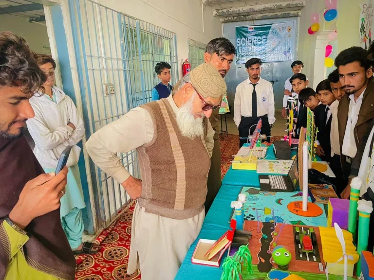 Elder visitor examining student projects at the Science and Arts Exhibition
