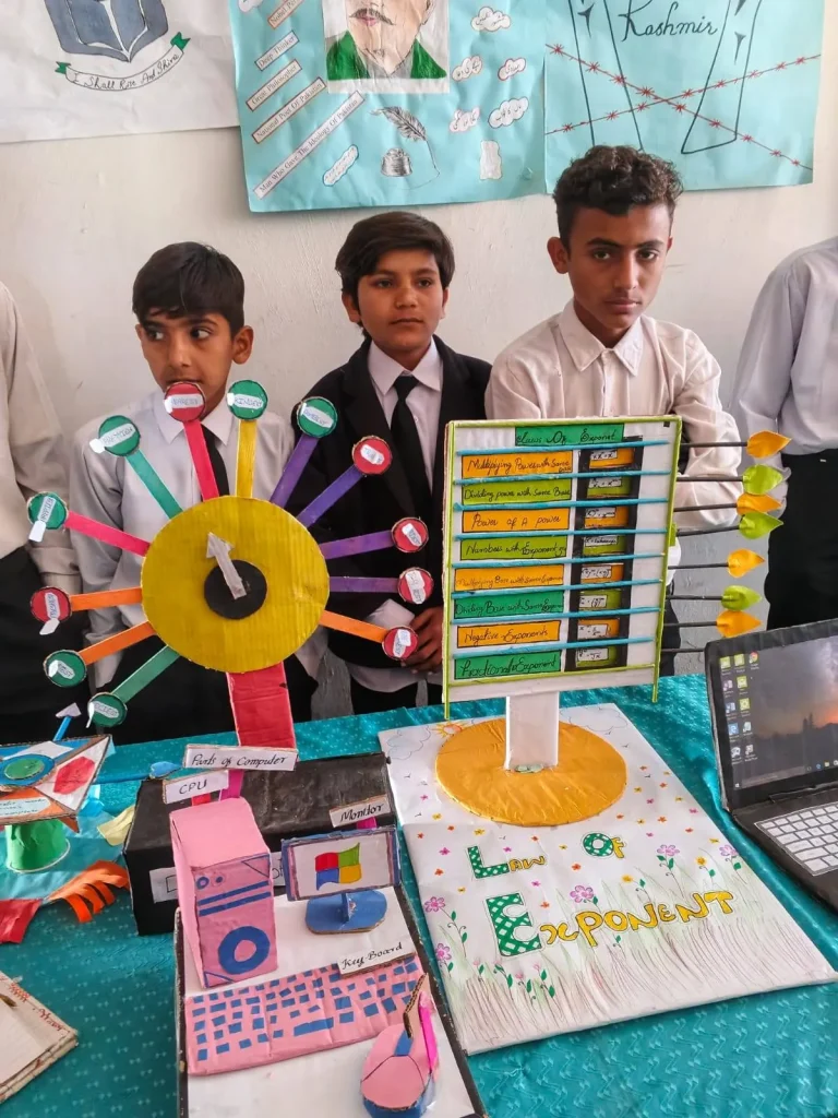 Students beside their colour wheel, laptop and chart display